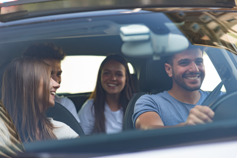 Vier junge Menschen sitzen lachend im Auto