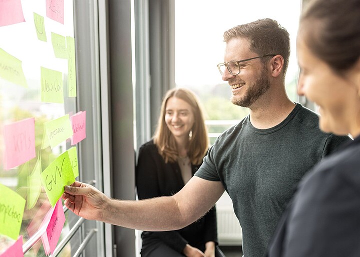 Drei GVV Mitarbeitende arbeiten zusammen an einem Whiteboard