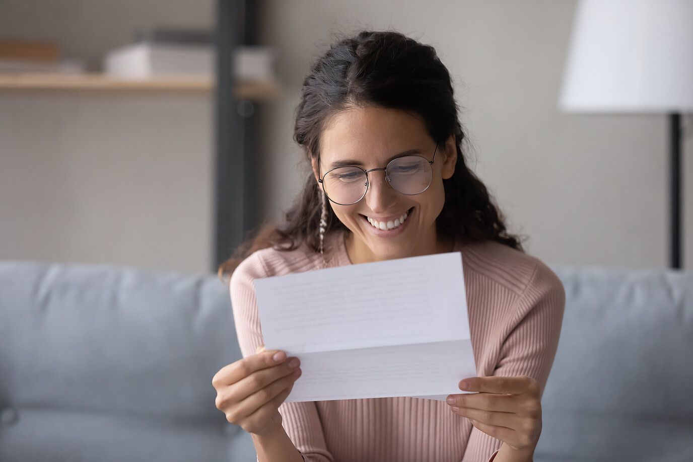 Eine Frau liest sich ein Dokument durch und freut sich. 