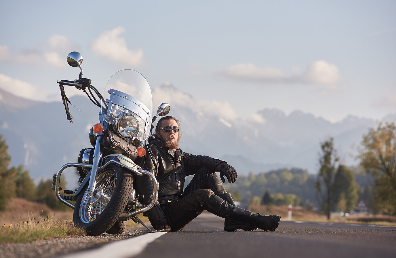 Motorradfahrer macht eine Pause und sitzt vor seinem Bike