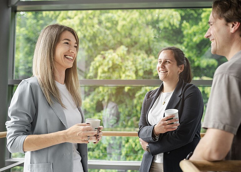Drei Mitarbeitende der GVV stehen lachend im Kreis unterhalten sich während der Kaffepause