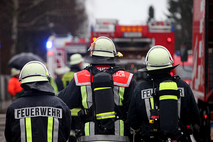 Drei Feuerwehrmänner von hinten in ihrer Feuerwehrkleidung