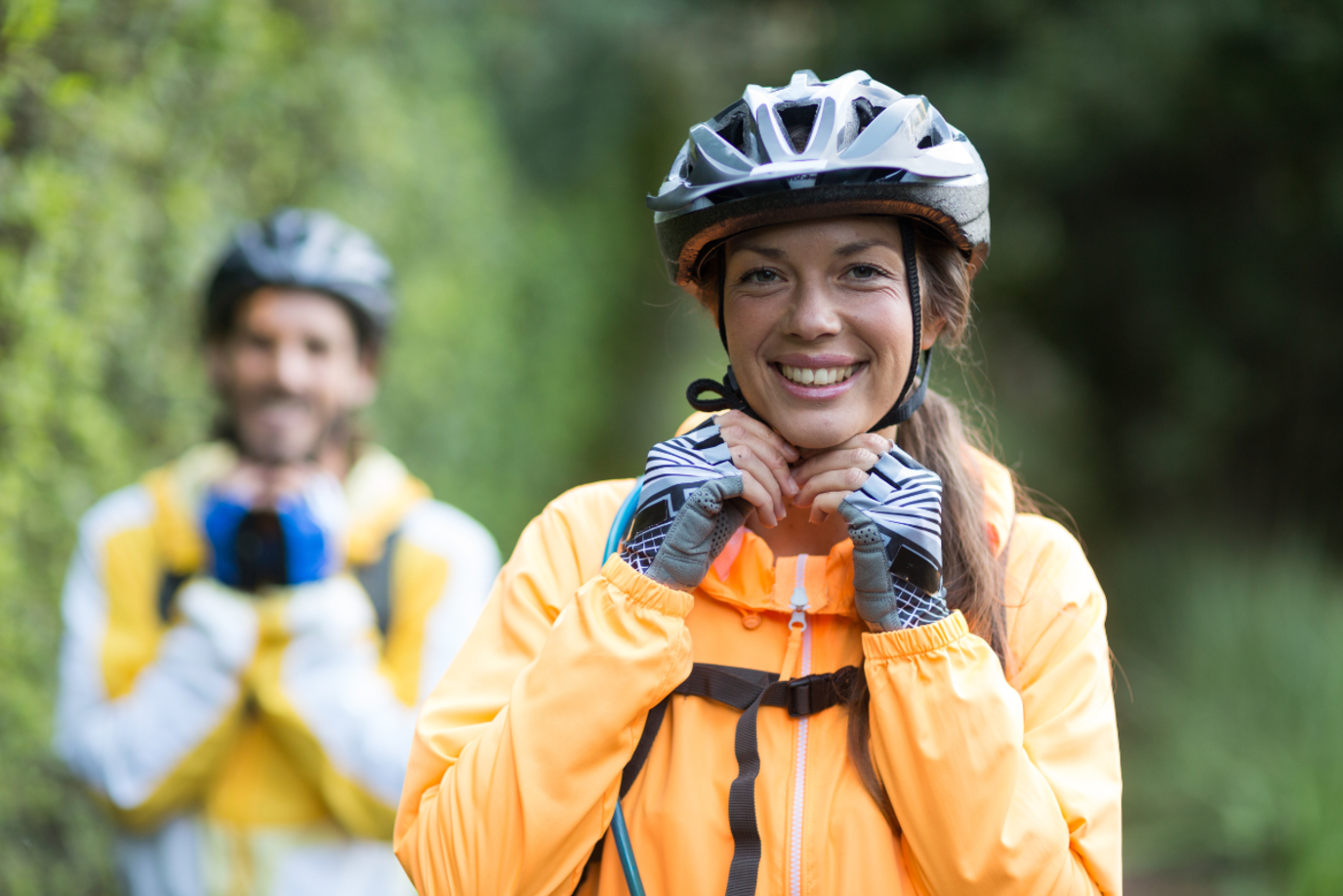 Eine Frau und ein Mann blicken mit Fahrradhelmen auf dem Kopf grinsend in die Kamera