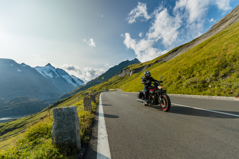 Ein Motorradfahrer fährt auf einer Straße in den Alpen