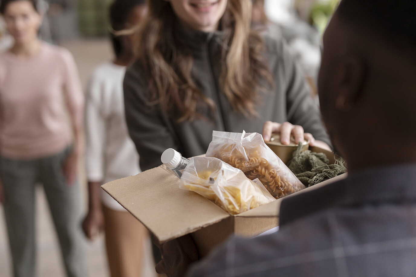 Freiwillige, die eine Spendebox mit Essen füllen