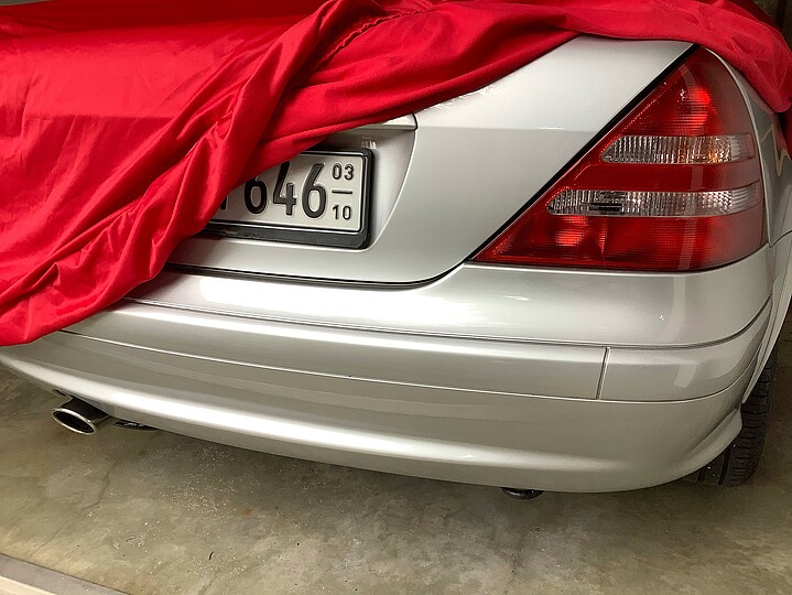 Ein Auto mit Saisonkennzeichen steht halb bedeckt in einer Garage