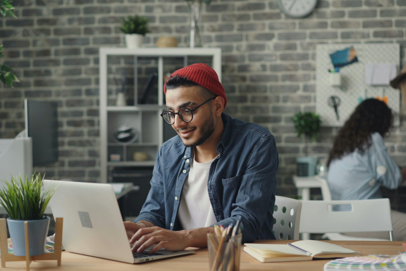 Junger Mann sitzt zufrieden am Laptop und tippt