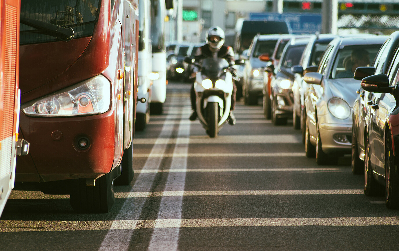 Ein Motorrad steht zwischen Autos im Stau im Stadtverkehr