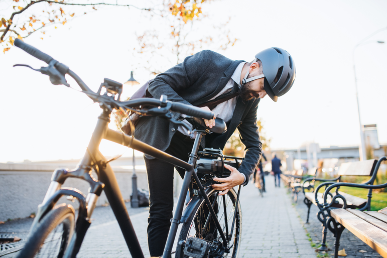 Mann im Anzug und Fahrradhelm schließt sein Fahrrad ab