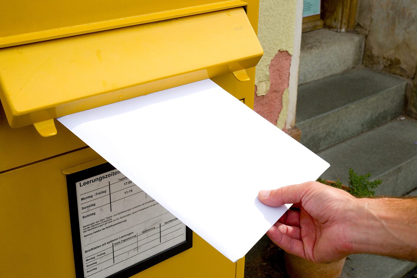 Jemand steckt ein Einschreiben in den Briefkasten