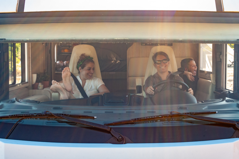 Gut gelaunte Familie mit Mutter, Vater und kleinem Sohn im Wohnmobil auf dem Weg in den Urlaub