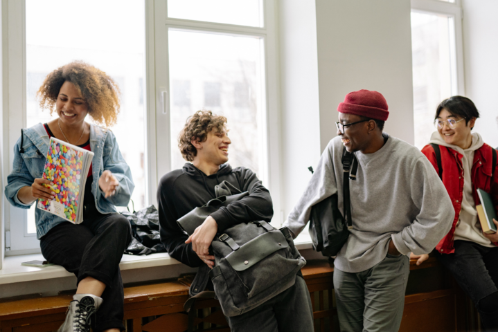 Vier junge Menschen lachend im Flur einer Universität