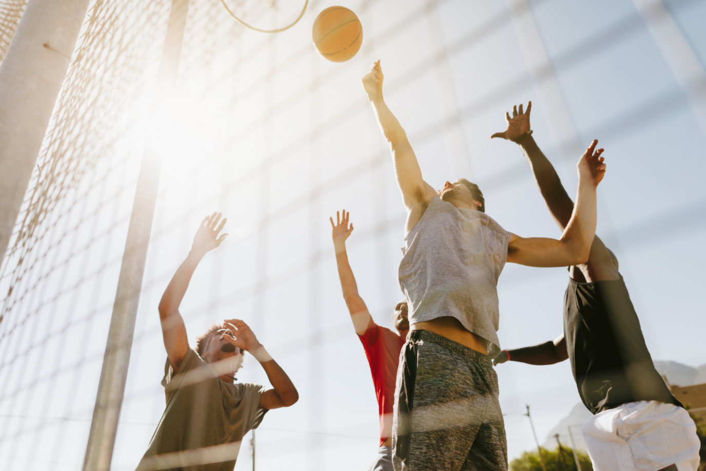 Vier junge Männer beim Basketball spielen vorm Korb