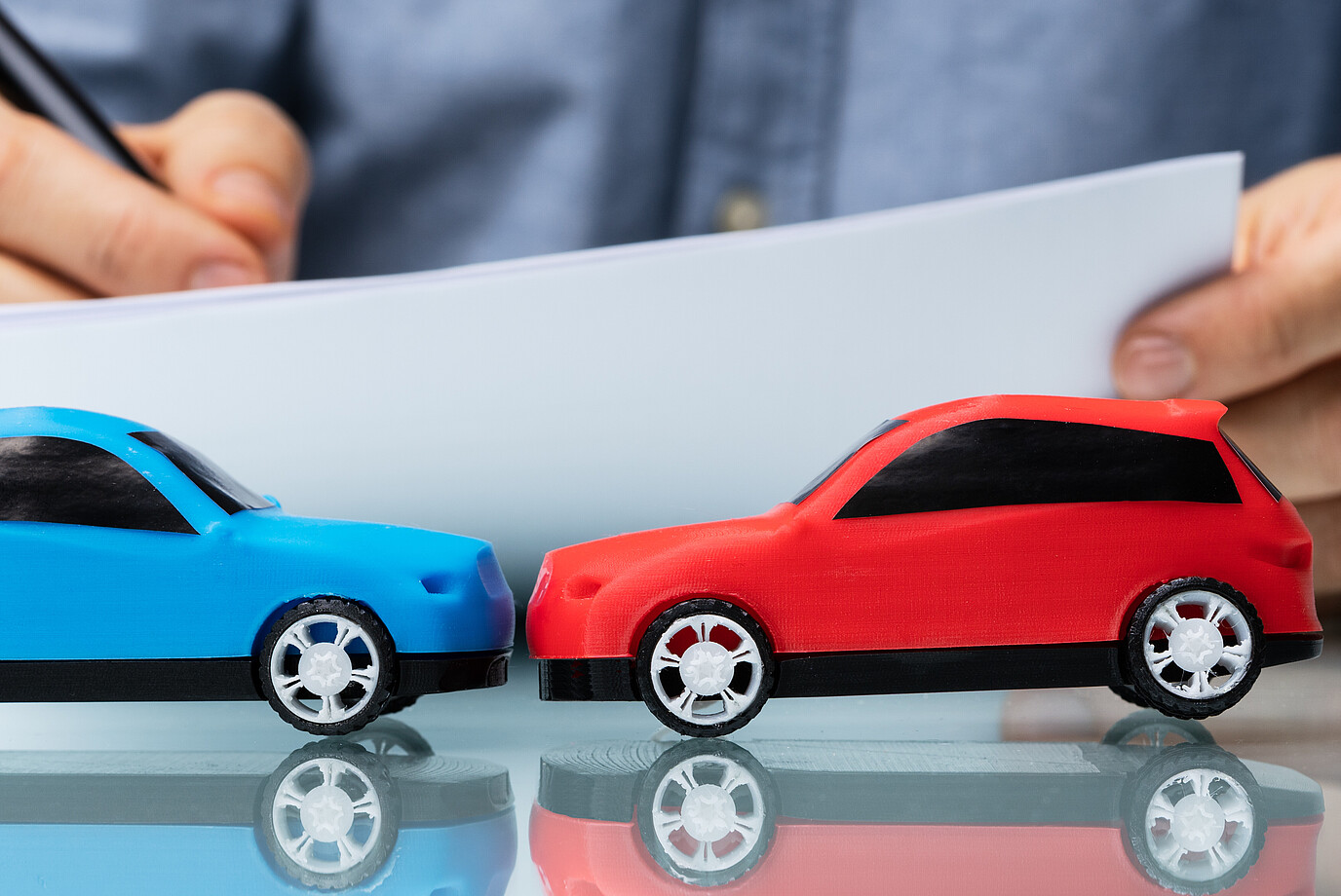 Zwei kleine Autos stehen vor einem Dokument. 