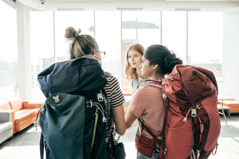 Drei junge Frauen Anfang 20 am Flughafen mit großen Rucksäcken