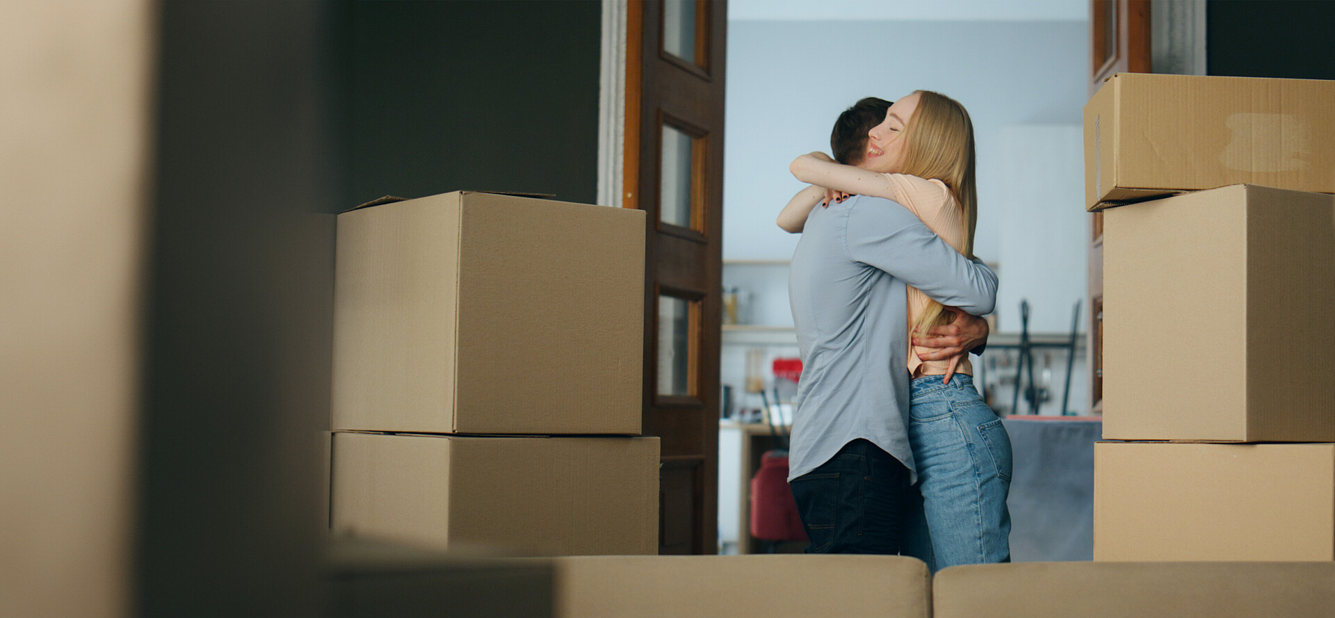 Mann und eine Frau umarmen sich in einer Wohnung mit vielen Umzugskartons