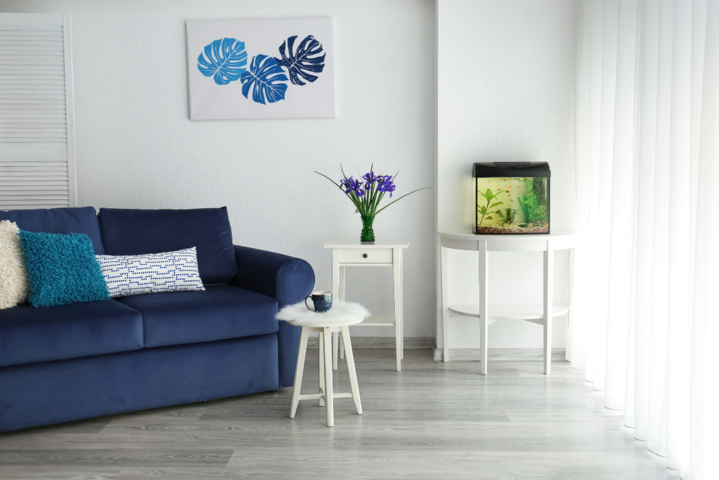 Kleines Aquarium mit Fischen im Wohnzimmer neben dem Sofa