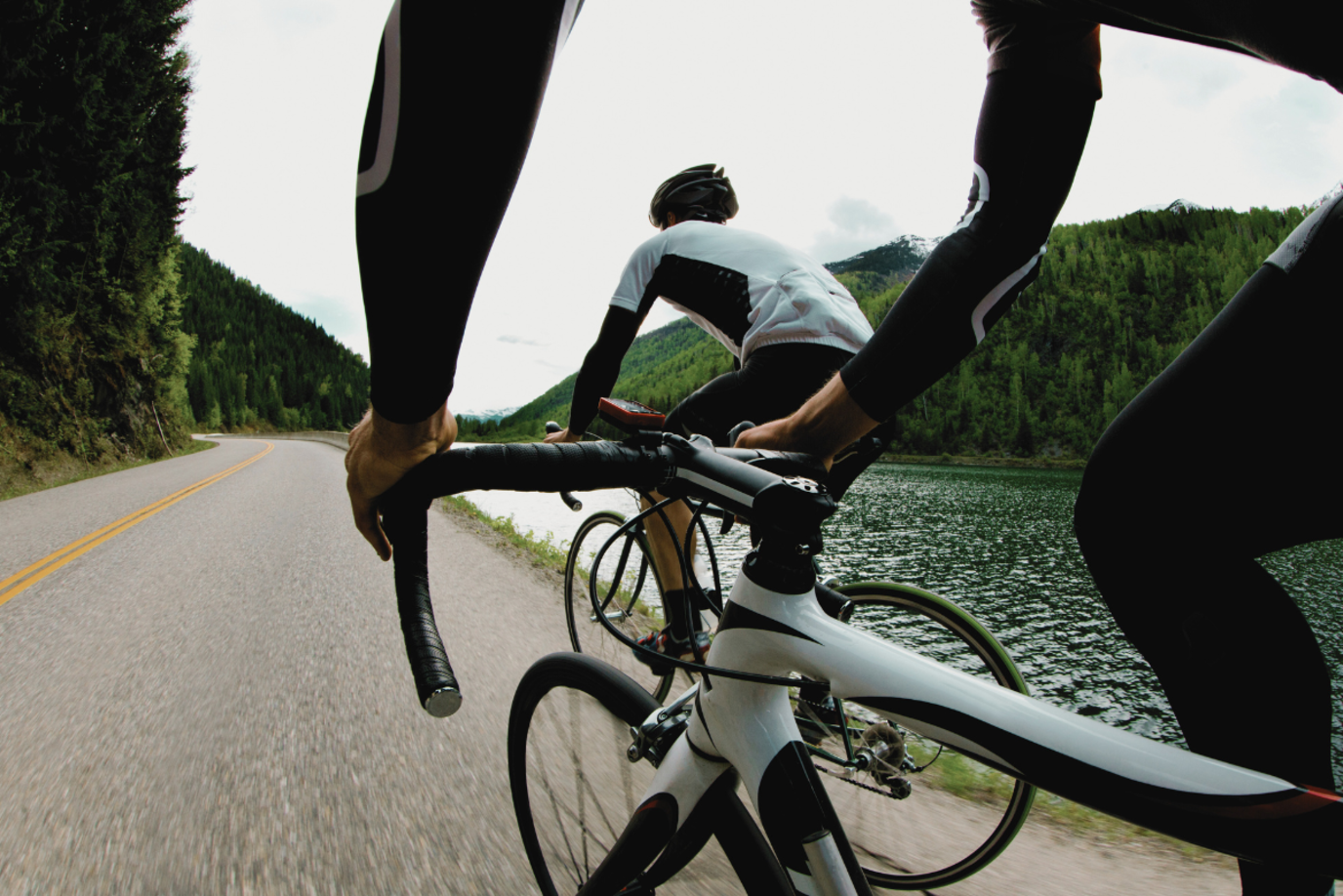 Zwei Rennradfahrer von hinten auf einer Straße am See