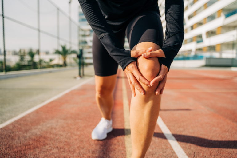 Close-Up auf das Knie einer Frau beim Dehnen vorm Joggen