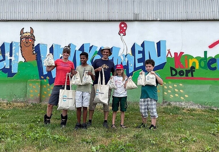 Kinder aus einem Kinderdorf halten freudig Spenden zum Fahrradfahren in die Kamera