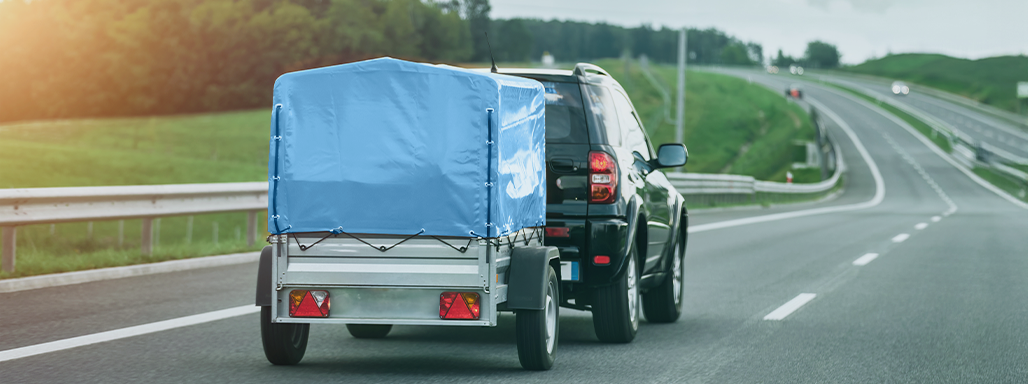 Ein Auto mit einem blauen Anhänger fährt auf der Autobahn.