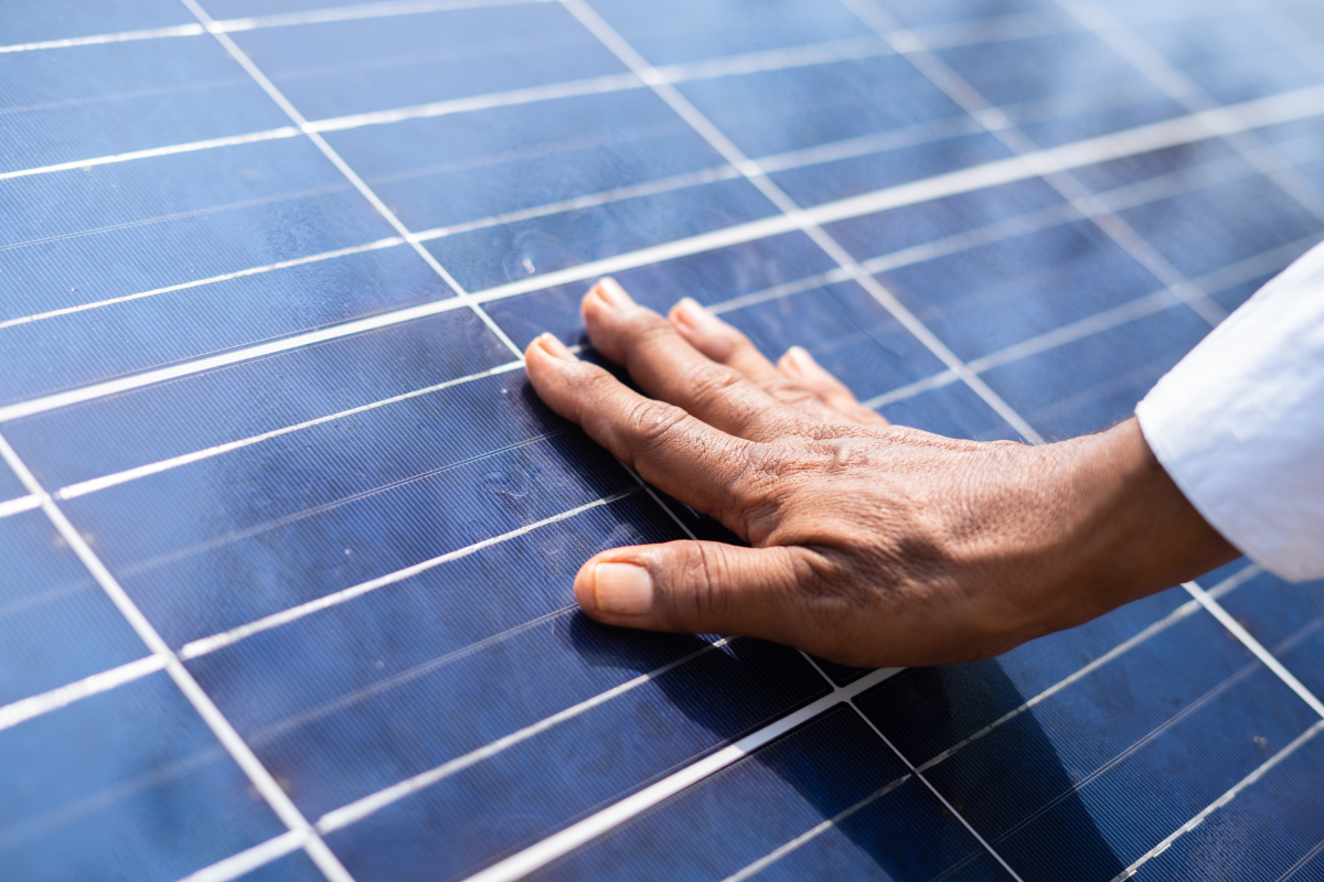 Close-Up auf eine Photovoltaikanlage, auf der eine Hand liegt