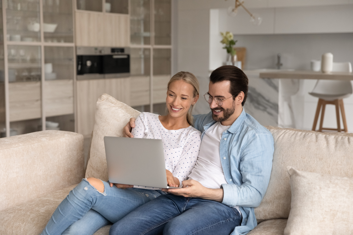 Junger Mann und junge Frau sitzen auf dem Sofa im Wohnzimmer an einem Laptop