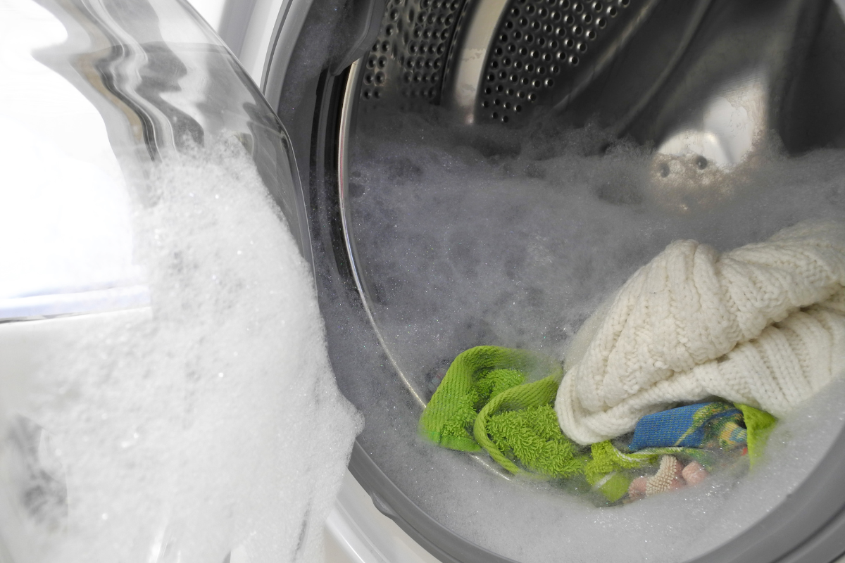 Geöffnete Waschmaschine mit Schaum und Wäsche in der Trommel