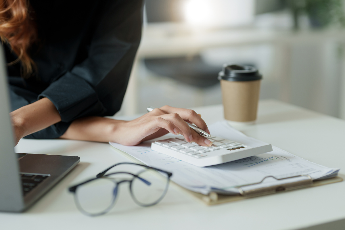 Eine Frau sitzt mit einem Taschenrechner am Schreibtisch