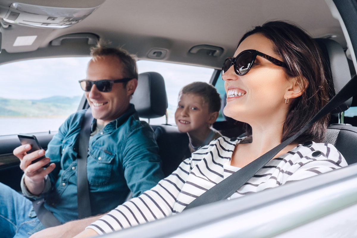 Gut gelaunte Familie mit Mutter, Vater und Kind sitzt im Auto und freut sich
